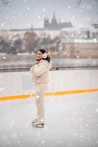 Schönes Mädchen amüsiert sich beim Eislaufen auf der Eisbahn auf dem Hintergrund des Prager Schlosses Tschechische Republik