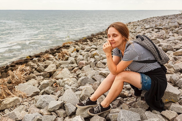 Schönes Mädchen auf dem Meer mit blauem Himmel und Wolken aus der Nähe