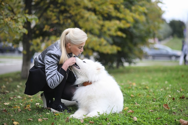 Schönes Mädchen auf einem Spaziergang mit einem schönen flauschigen Hund Samojede