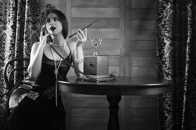 Schönes Mädchen aus den 1930er Jahren raucht eine Zigarette am Tisch