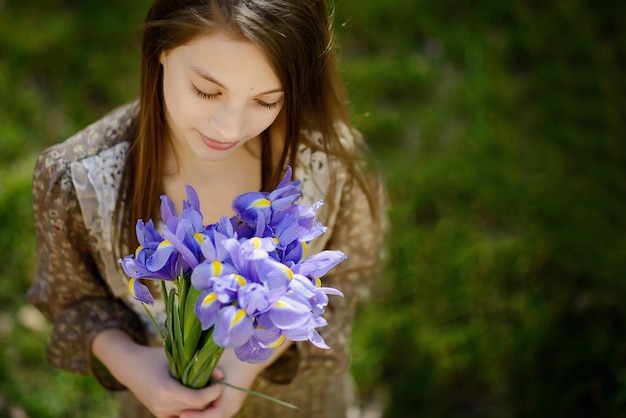 Schönes Mädchen betrachtet einen Blumenstrauß der Frühlingsblumen der Iris