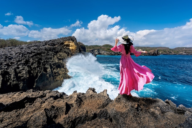 Schönes Mädchen, das auf dem Felsen bei Engels Billabong nahe gebrochenem Strand in Nusa penida Insel, Bali in Indonesien steht.