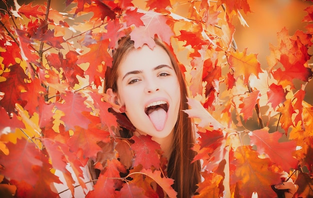 Schönes Mädchen, das den Herbst genießt Junge Frau mit Zunge und lustiger Herbststimmung