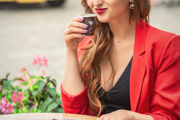 Schönes mädchen, das draußen kaffee im café trinkt.