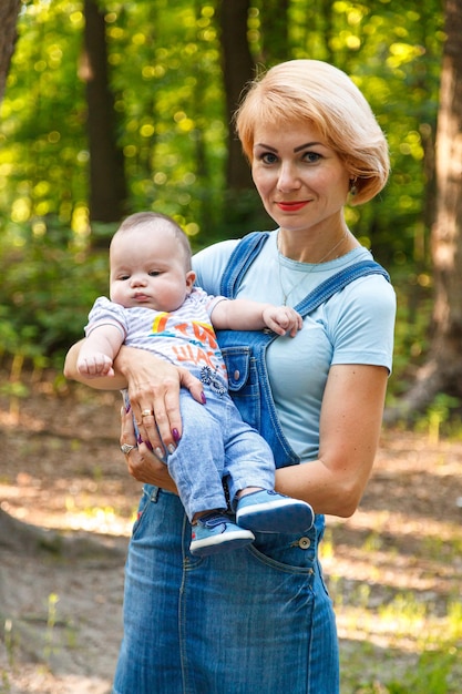 Schönes Mädchen, das ein Kind in ihren Armen in einem Sommerpark hält