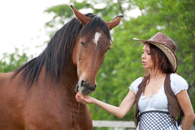 Schönes Mädchen, das ein Pferd füttert