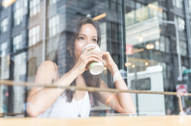 Schönes Mädchen, das einen heißen Kaffee in einem Geschäft in New York genießt