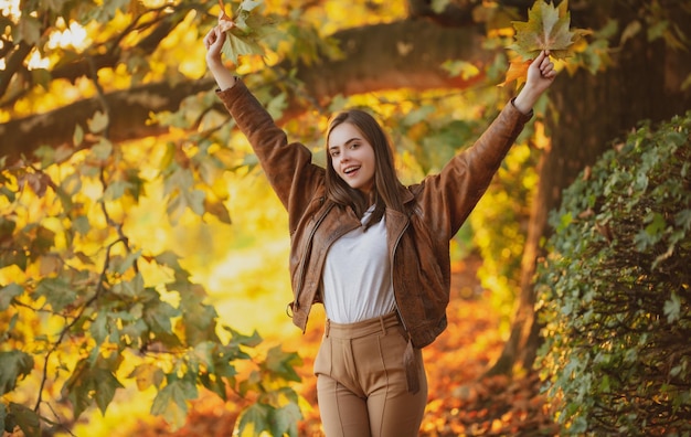 Schönes Mädchen, das Herbstporträt der jungen Frau im Freien auf Herbsthintergrund genießt