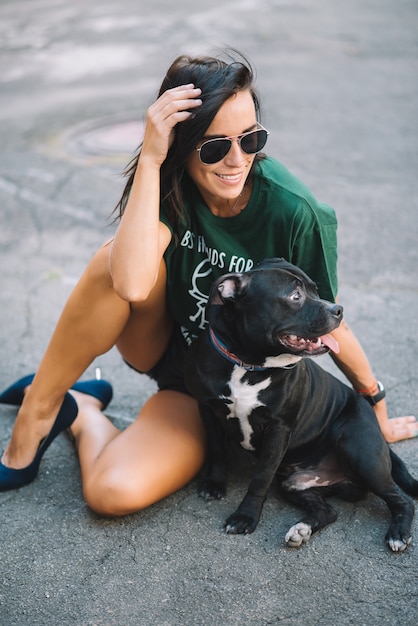 Schönes Mädchen, das ihren Haustierhund Staffordshire Bullterrier im Freien an sonnigem Tag im Sommer sitzen Straße.