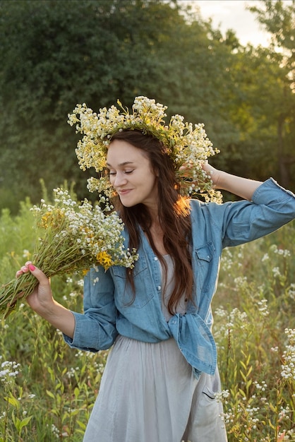 Schönes Mädchen, das im Sommer mit Wildblumen auf dem Feld spazieren geht