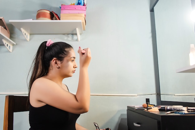 Schönes Mädchen, das in ihrem Zimmer ein Make-up-Puder aufträgt.