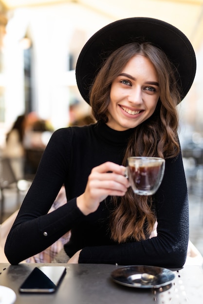 Schönes Mädchen, das Kaffee im Café im Freien hat