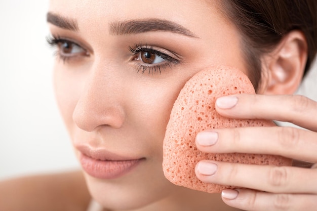 Schönes Mädchen, das Make-up mit einem herzförmigen Schwamm macht