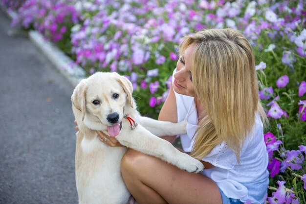 Schönes Mädchen, das mit einem Welpen Labrador spielt