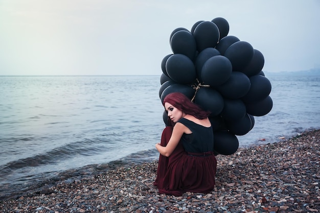 Schönes Mädchen, das mit schwarzen Ballons geht