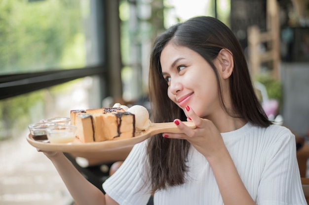 Schönes Mädchen, das Nachtisch in der Kaffeestube hält