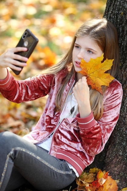 Schönes Mädchen, das Selfie per Smartphone im Herbststadtpark macht