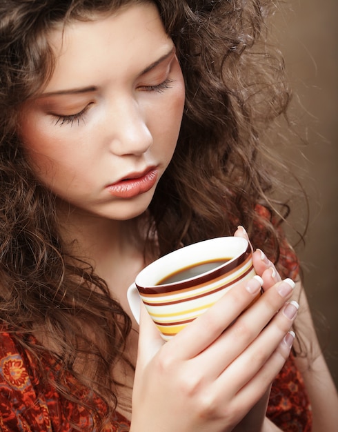 Schönes Mädchen, das Tee oder Kaffee trinkt.