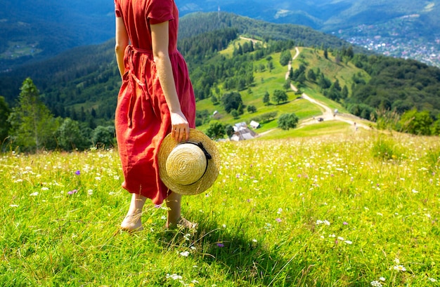 Schönes Mädchen die Berge. Frau im Leinenkleid und im Strohhut unterwegs. Erstaunliche Sommernatur herum.