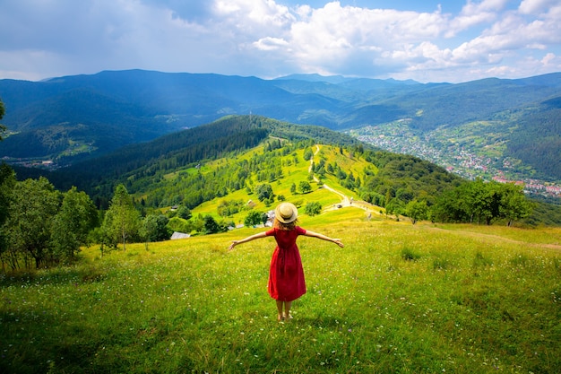 Schönes Mädchen die Berge. Frau in Leinenkleid und Strohhut auf Reisen. Erstaunliche Sommernatur herum. Harmonie und Fernweh-Konzept. Rustikaler Naturstil. Wind weht für dynamisches Foto.