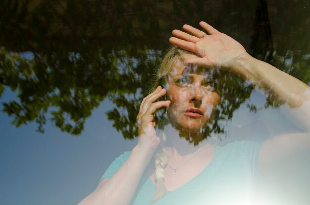 Foto schönes mädchen empfangen schlechte nachrichten über handy, schauen durch fenster und lehnen ihre palme