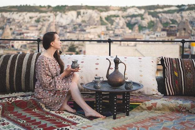 Schönes Mädchen entspannt sich bei einer Tasse Tee auf dem Sofa im türkischen Stil und Interieur