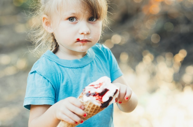 Schönes Mädchen fünf Jahre, das Eis in der Natur isst, das Horn mit Früchten