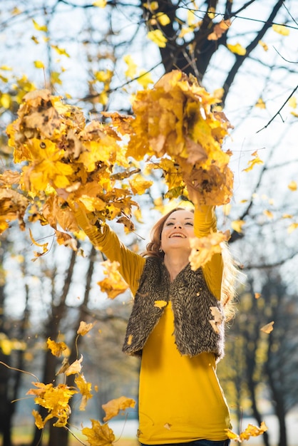 Schönes Mädchen geht im Herbstpark mit gelben gefallenen Blättern spazieren