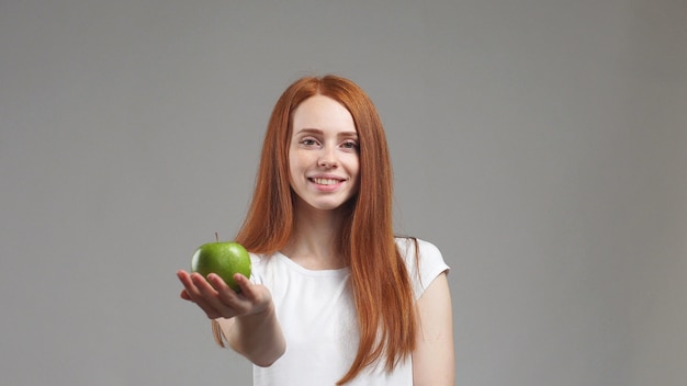 Schönes Mädchen hält einen grünen Apfel in ihrer rechten Hand