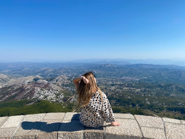 Schönes Mädchen hoch über den Bergen, das eine atemberaubende Aussicht genießt und die Freiheit des Träumens entspannt