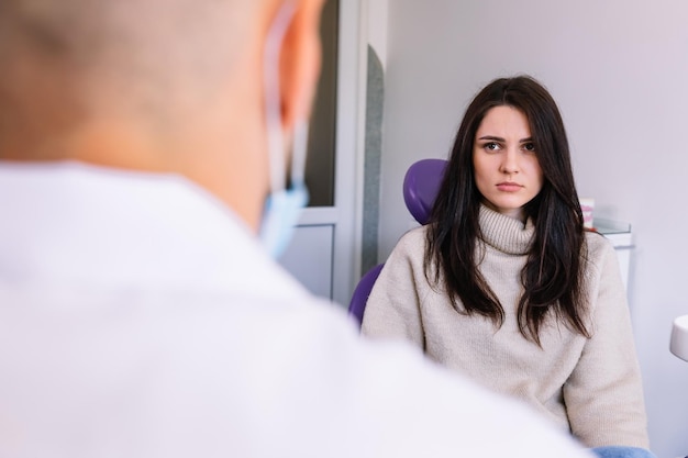 Schönes Mädchen hört dem Zahnarzt im Consultat aufmerksam zu