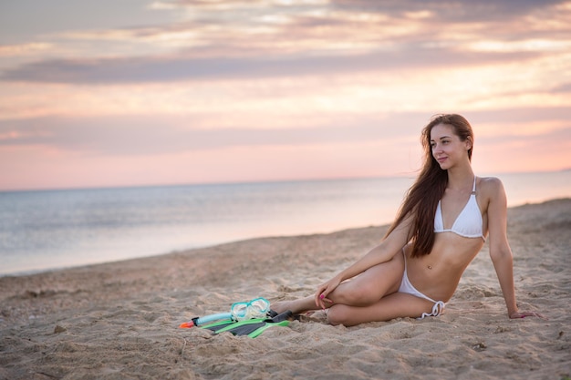 Schönes Mädchen im Badeanzug am Strand bei Sonnenuntergang