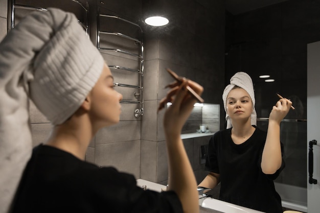 Schönes Mädchen im Badezimmer schminkt sich nach einer Dusche