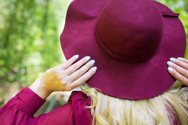 Schönes Mädchen im Kirschkleid mit einem Hut im Holz