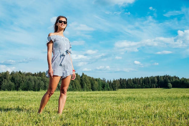 Schönes Mädchen im Kleid auf grünem Feld. Menschen- und Naturkonzept