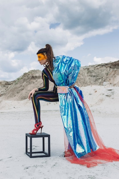 Foto schönes mädchen im kreativen festivaloutfit, gelbe plastikmaske und blau glänzende haube