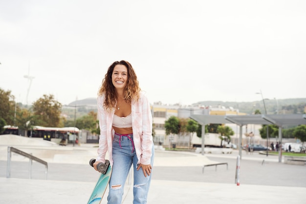 Schönes Mädchen im Park mit einem Skateboard