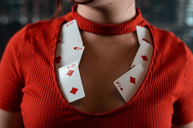 Schönes Mädchen im roten Kleid mit einem Ausschnitt, in dem Pokerkarten Frau in Pokerspielen der Aufregung des Zufalls