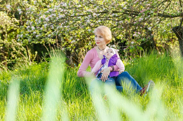 Schönes Mädchen in den Armen eines Kindermädchens in einem blühenden Park