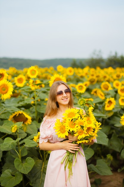 Schönes Mädchen in den Sonnenblumen im Sonnenuntergang