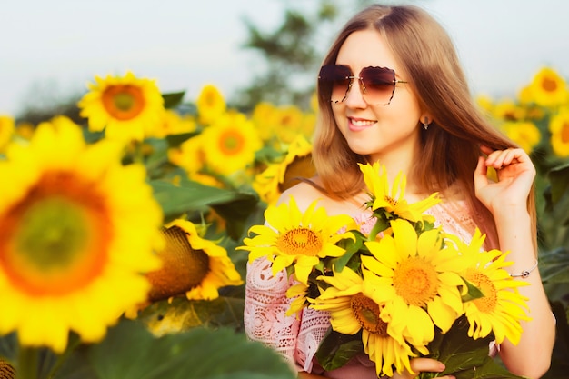 Schönes Mädchen in den Sonnenblumen im Sonnenuntergang