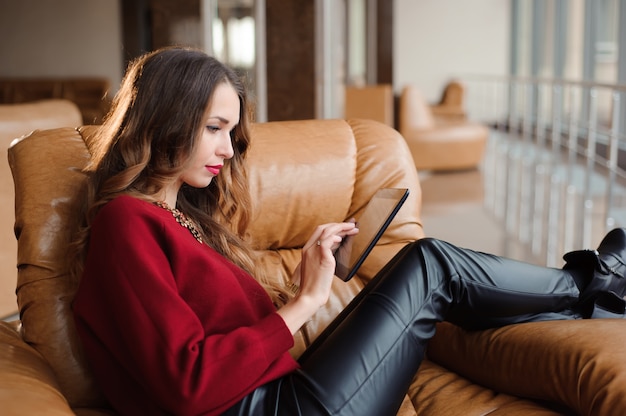 Schönes Mädchen in der Flughafenlounge mit einer Tablette