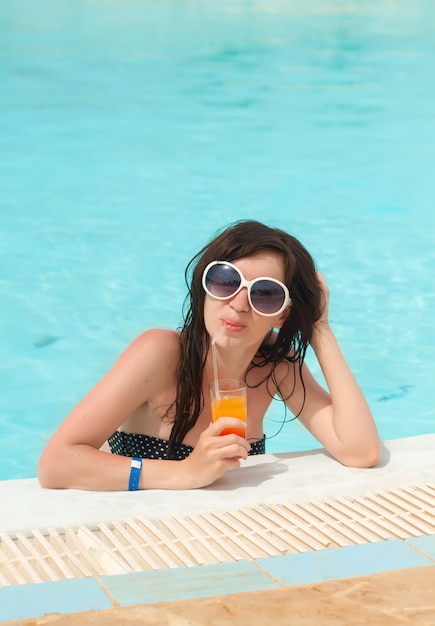 Schönes Mädchen in der Sonnenbrille mit frischem Wassermelonensaft im Luxuspool