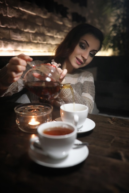 Schönes Mädchen in einem Café, das bei einem Abendessen eine Tasse Kaffee trinkt