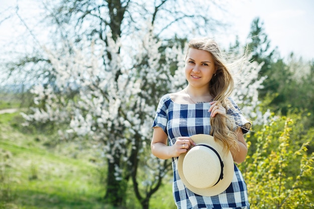 Schönes Mädchen in einem Kleid, das im Frühlingswald spaziert, wo die Bäume blühen