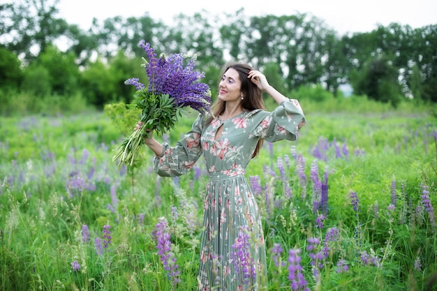 Schönes Mädchen in einem Kleid mit einem Lavendelblumenstrauß in einem Feldhintergrund