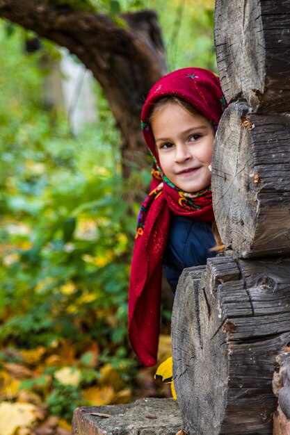 Schönes Mädchen in einem leuchtend roten Schal. Porträt eines Mädchens mit braunen Augen in einem alten russischen Schal auf dem Hintergrund des Herbstes. Foto-Shooting