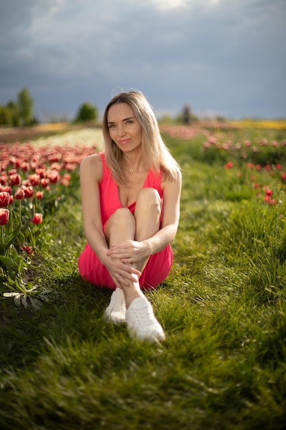 Schönes Mädchen in einem rosa Kleid in einem Park mit Tulpen