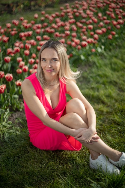 Schönes Mädchen in einem rosa Kleid in einem Park mit Tulpen