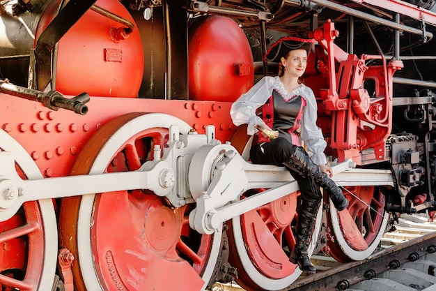 Schönes Mädchen in einem Steampunk-Anzug auf dem Hintergrund eines alten Zuges